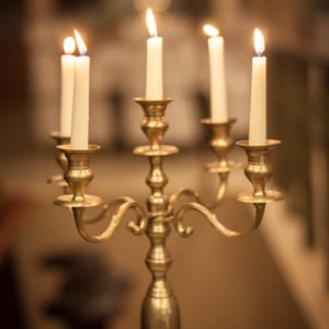 Fünfarmiger goldener Kerzenständer mit brennenden Kerzen