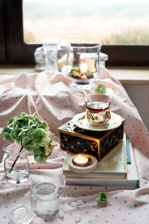 Gedeckter Tisch zu Teezeit mit Deko und kleinen Teelichthaltern