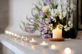 Reihe von vielen kleinen Kerzen und Teelichtern auf dem Kaminsims